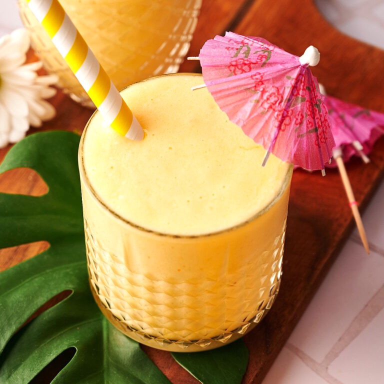 Tropical smoothie in glass with pink umbrella.
