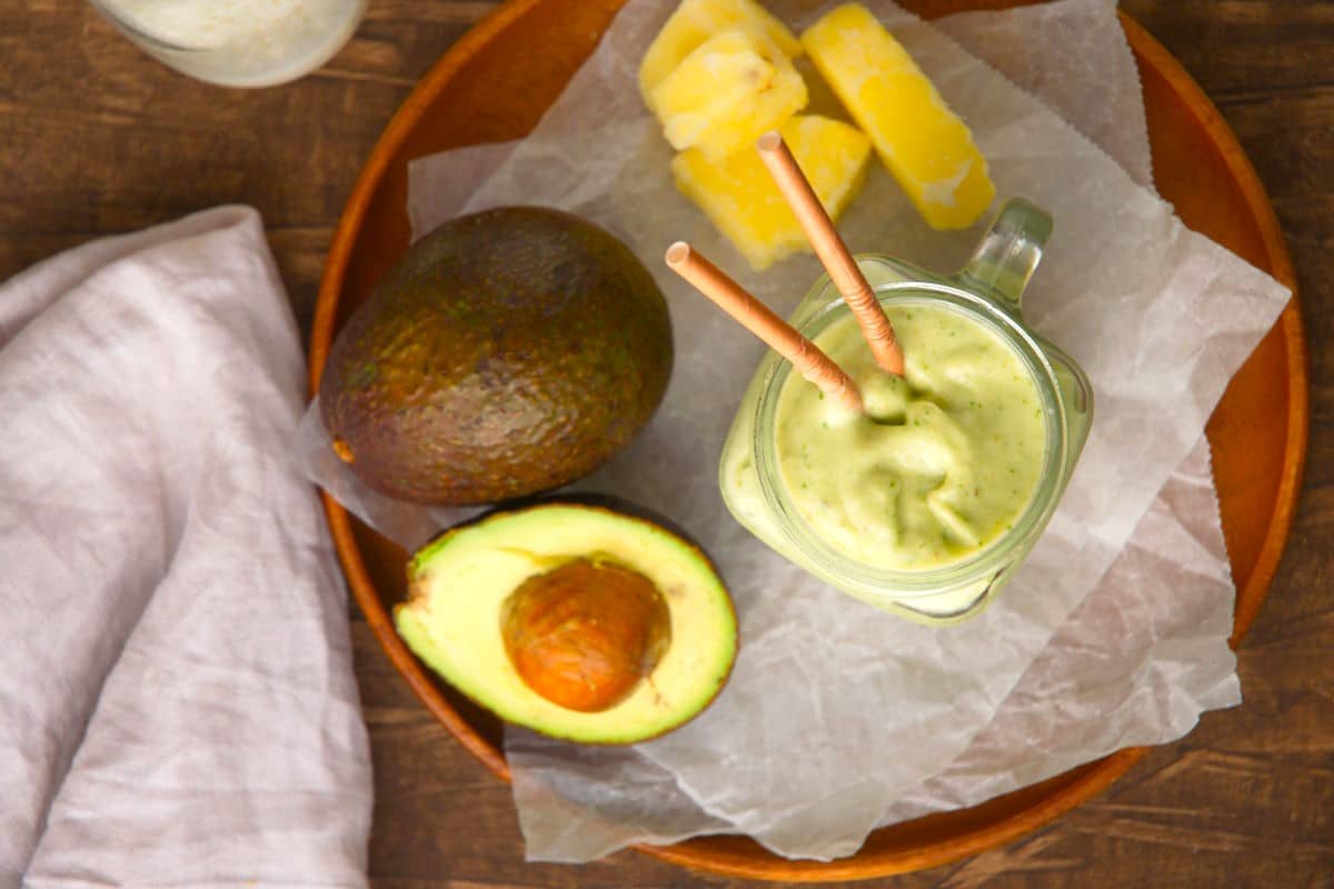 Avocado smoothie, fresh avocados and pineapple on parchment lined tray.