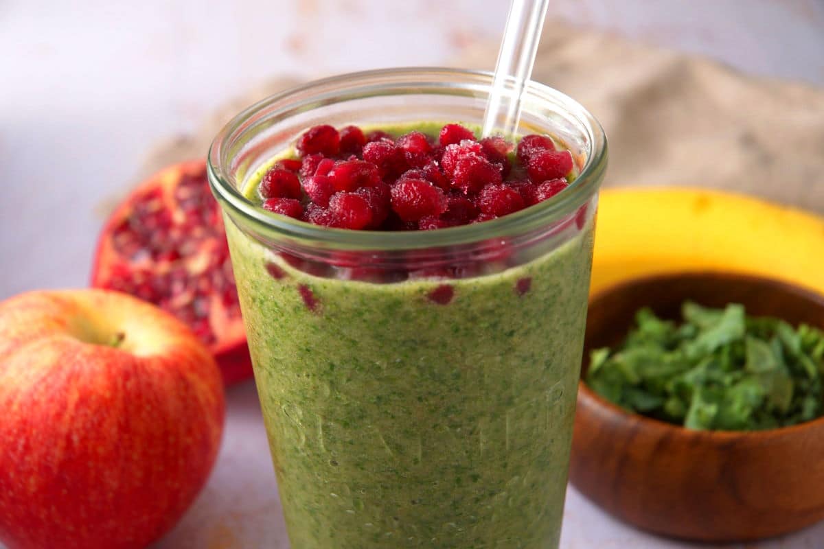Kale smoothie with pomegranate seed topping in glass.