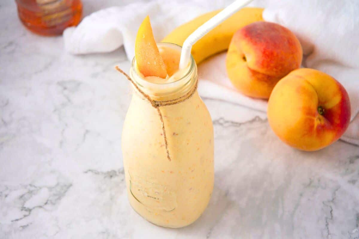 Peach smoothie in jar with straw.