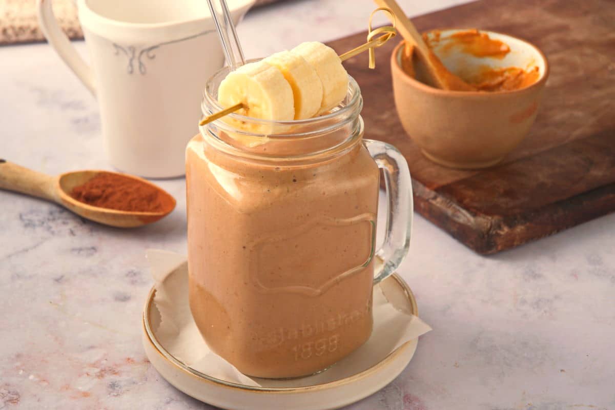 Peanut butter banana smoothie in a jar on marble background.