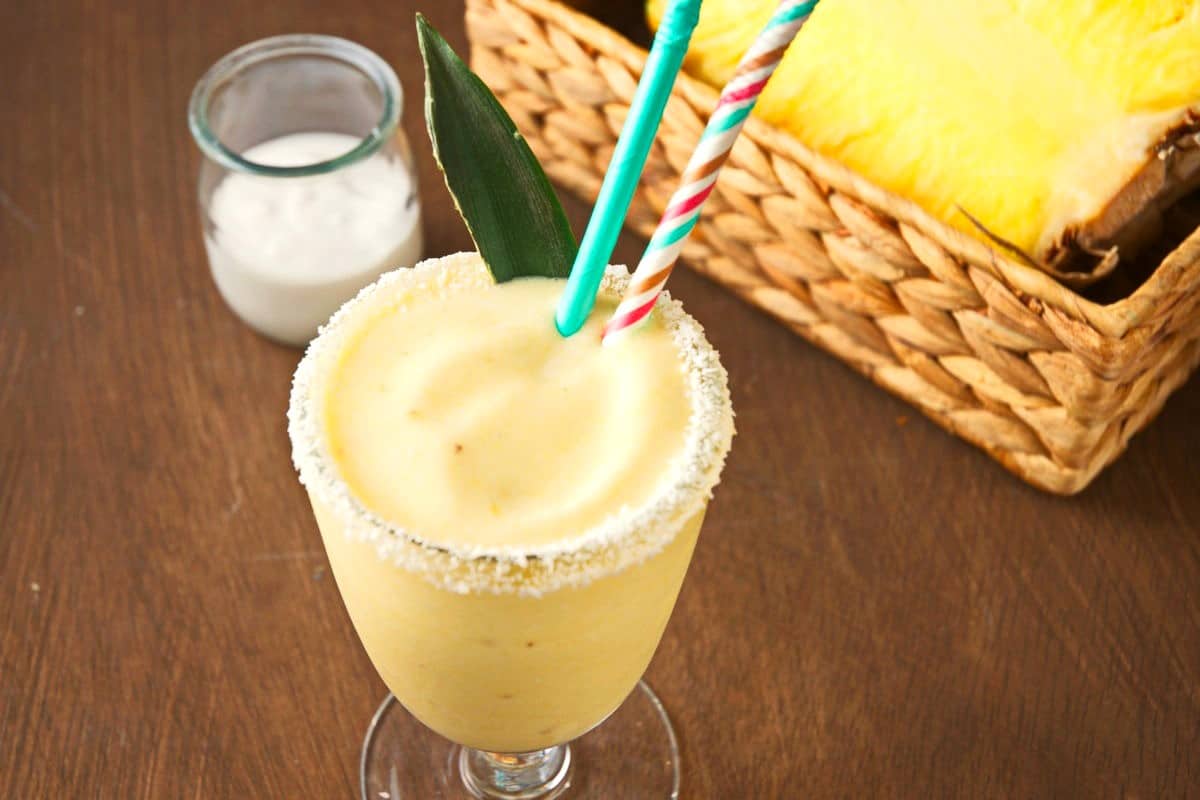 Piña Colada smoothie in glass with coconut rim.