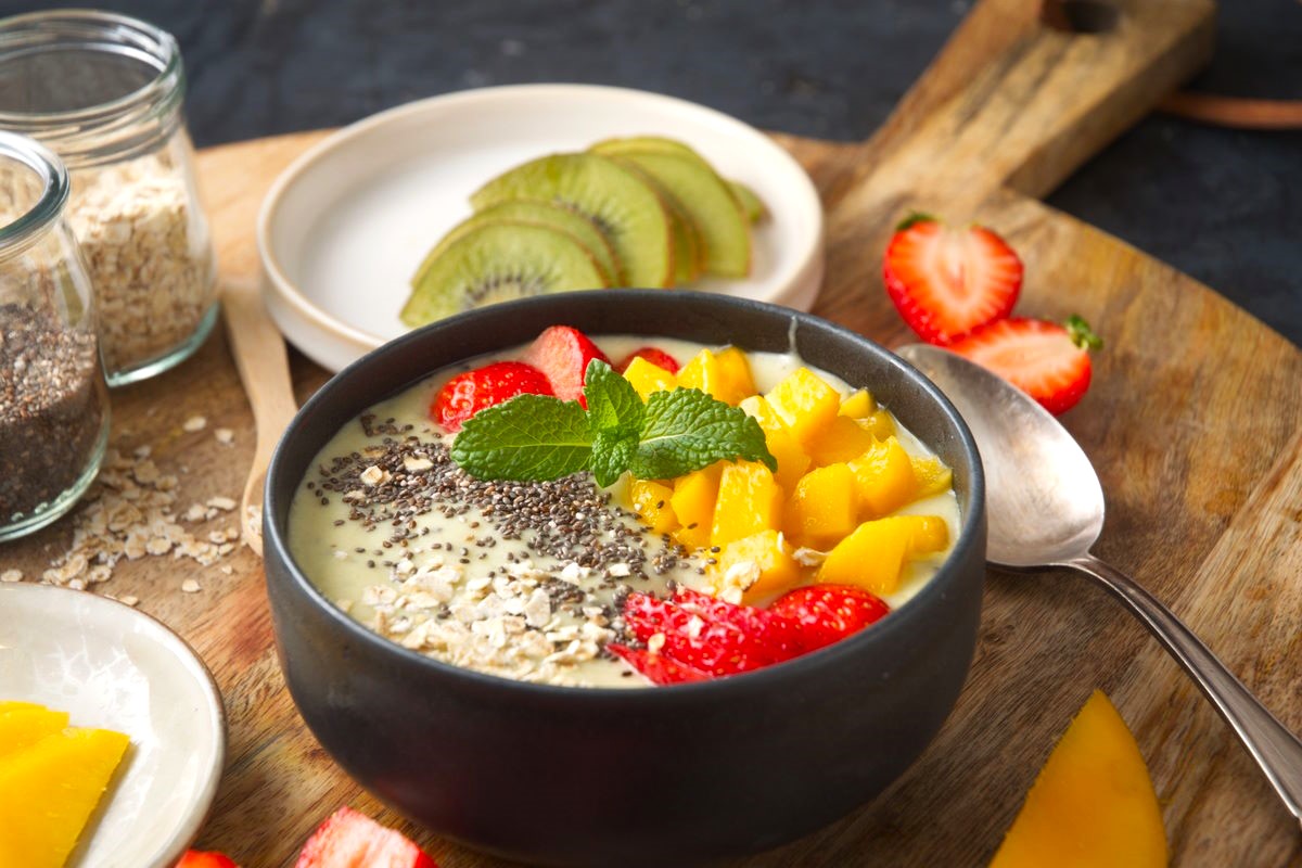 Kiwi fruit smoothie bowl with grains in dark bowl.