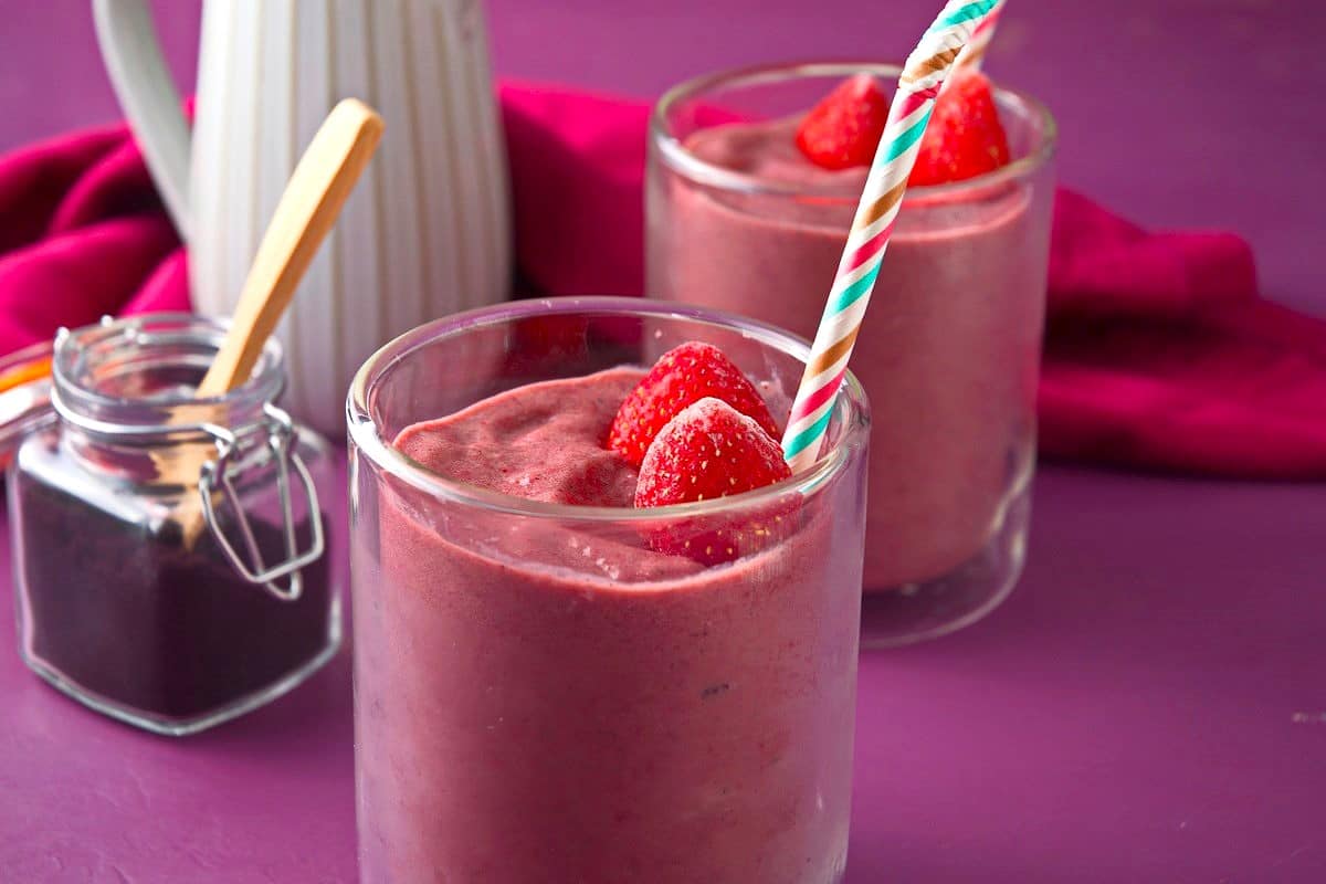 Acai smoothie in glasses with colorful straws.