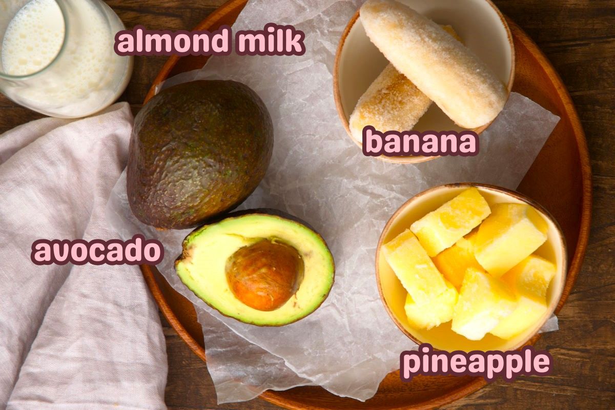 Avocado smoothie ingredients labeled on wooden tray.
