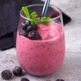 Blueberry keto smoothie in glass with fresh mint.