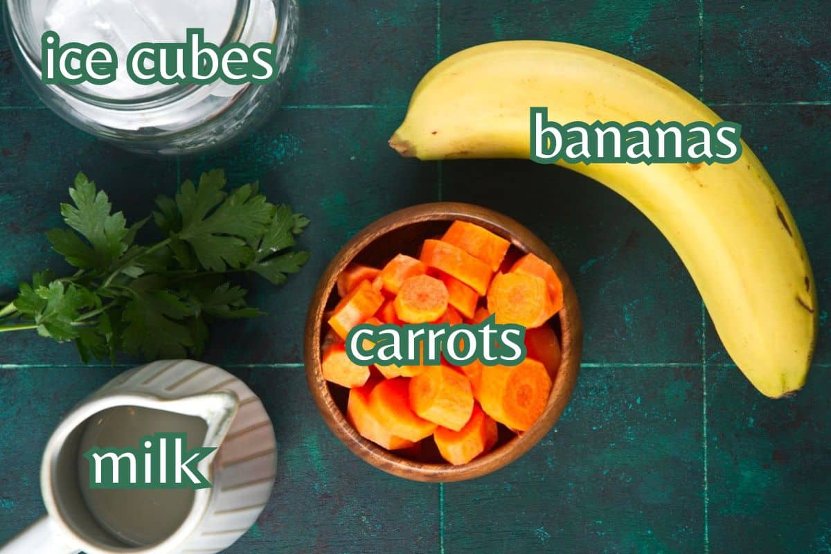 Carrot smoothie ingredients prepped on dark teal background.