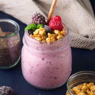 Chia seed smoothie in jar topped with granola and mixed berries.