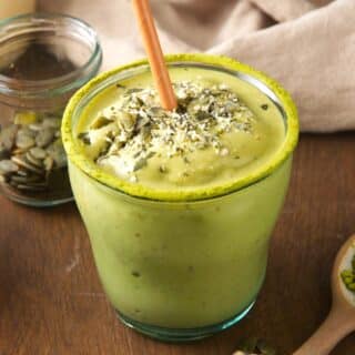 Matcha smoothie in a glass with brown paper straw.