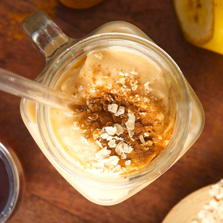 Oatmeal smoothie in glass jar topped with oats and cinnamon powder.