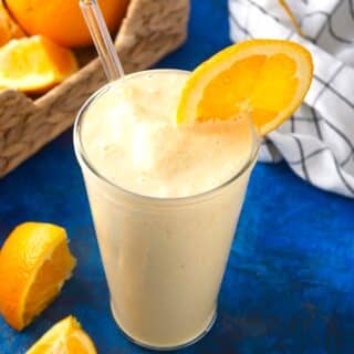 Orange smoothie in glass with orange slice.