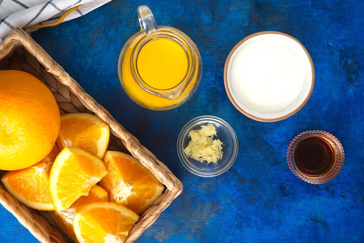 Orange smoothie ingredients on royal blue background.