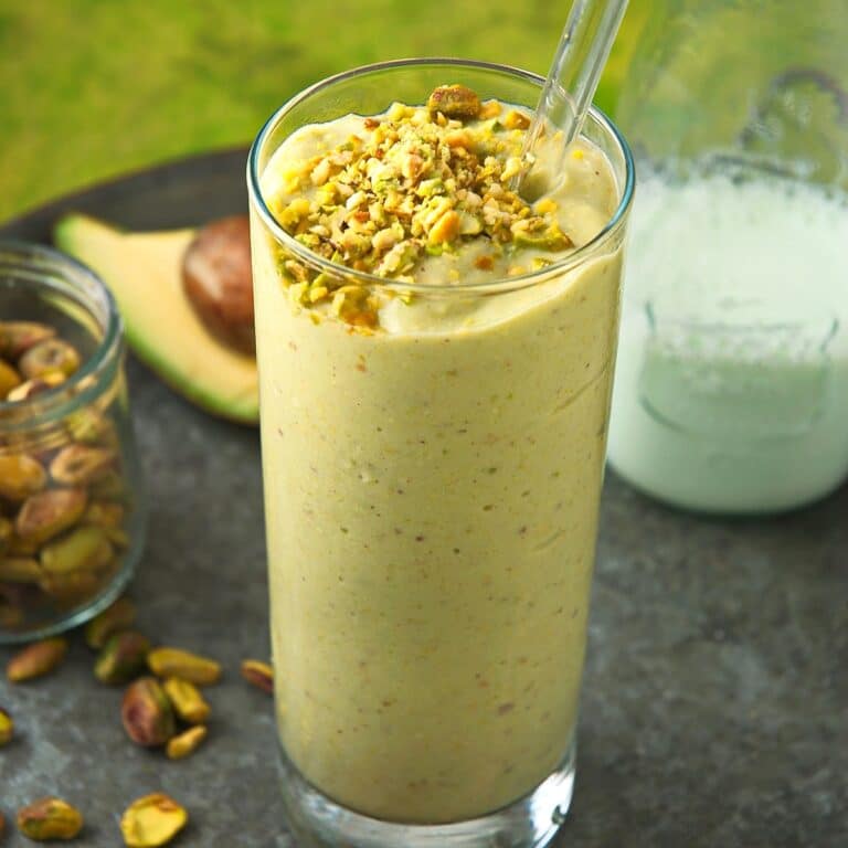 Pistachio smoothie in a glass with clear straw.