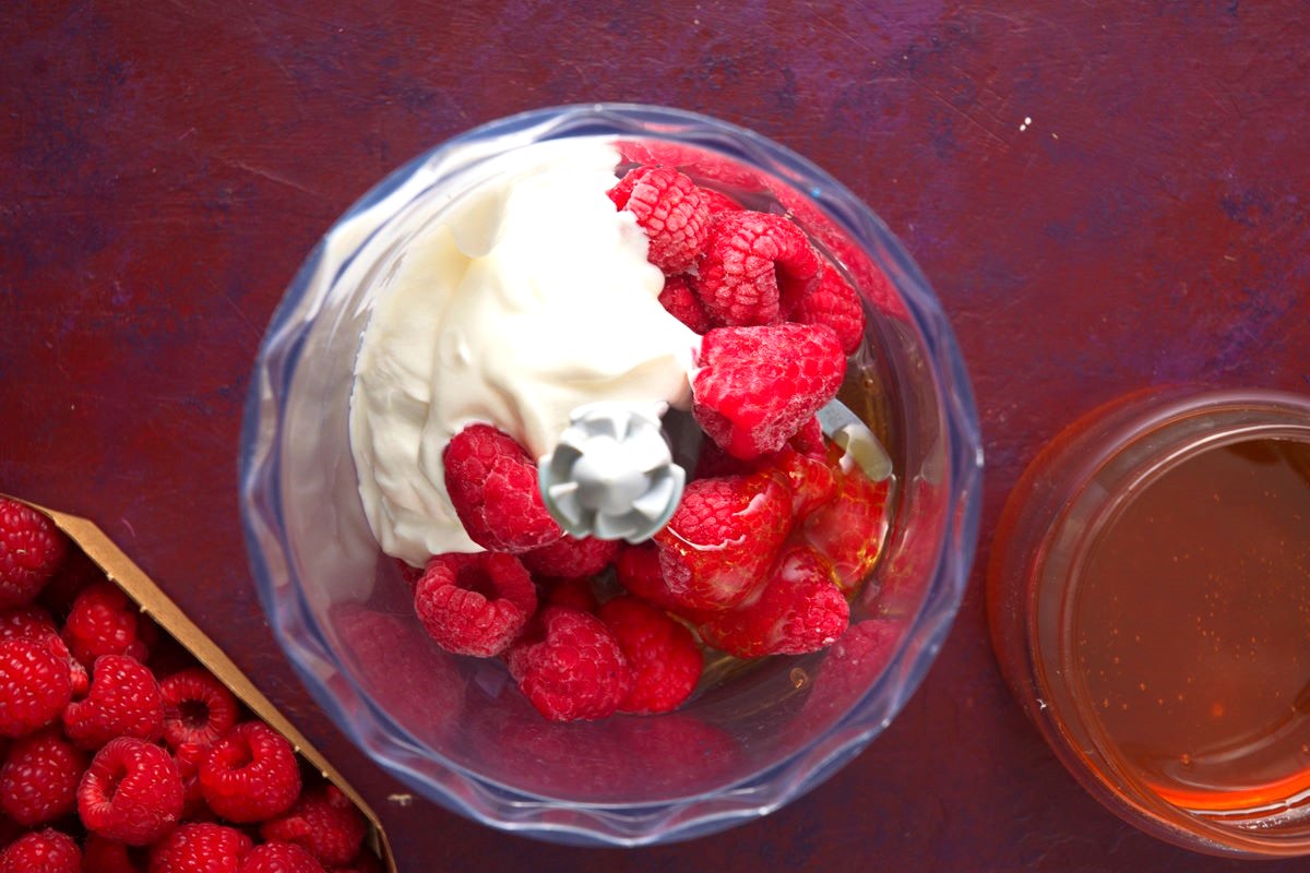 Raspberry smoothie ingredients in food processor.