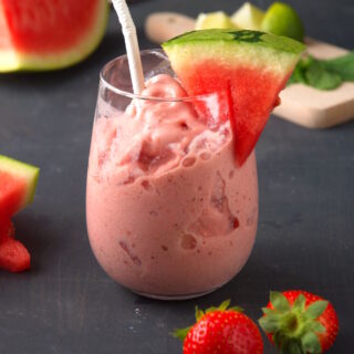Watermelon smoothie in glass with white straw.